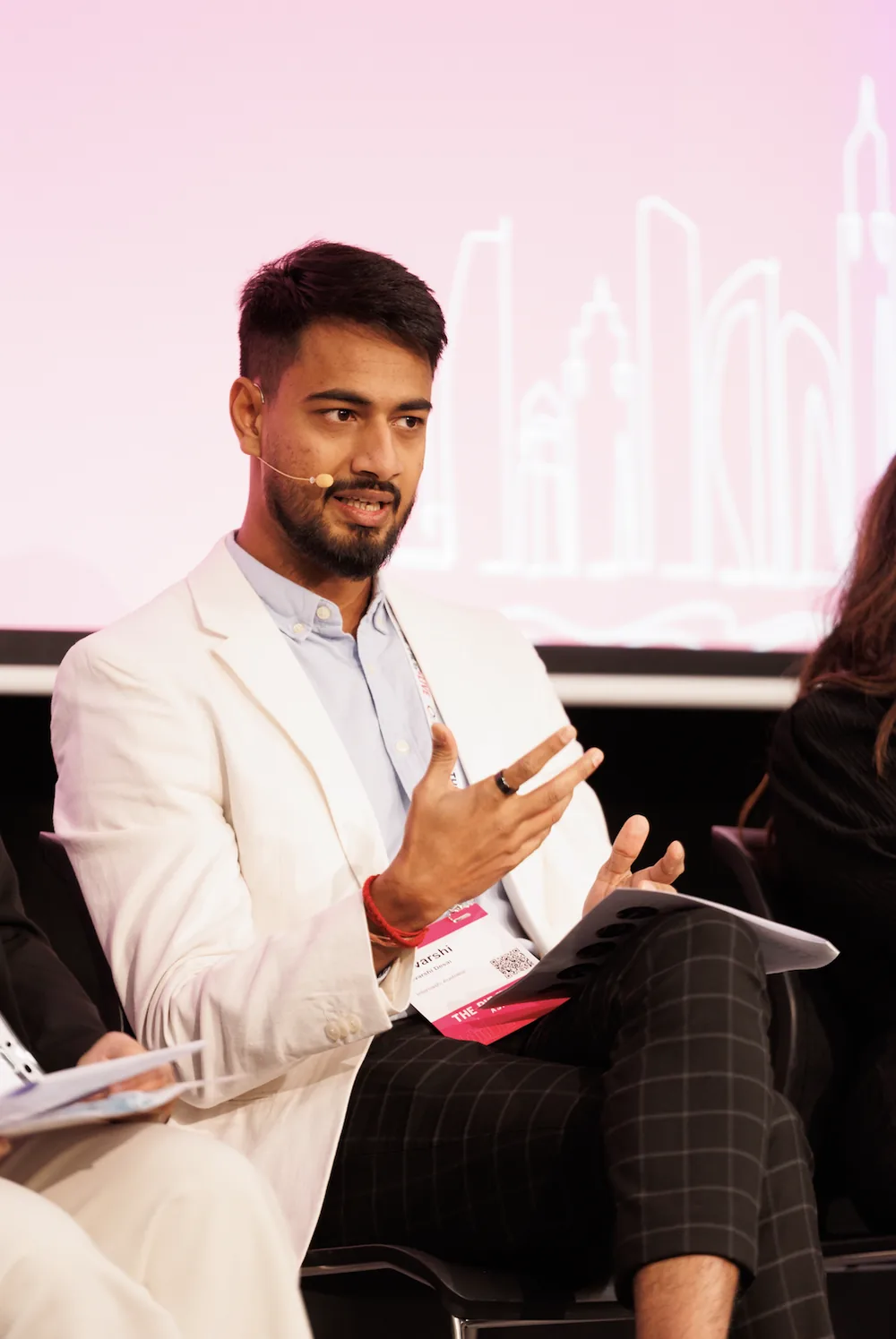 Devarshi Desai speaking on a conference panel in a white blazer